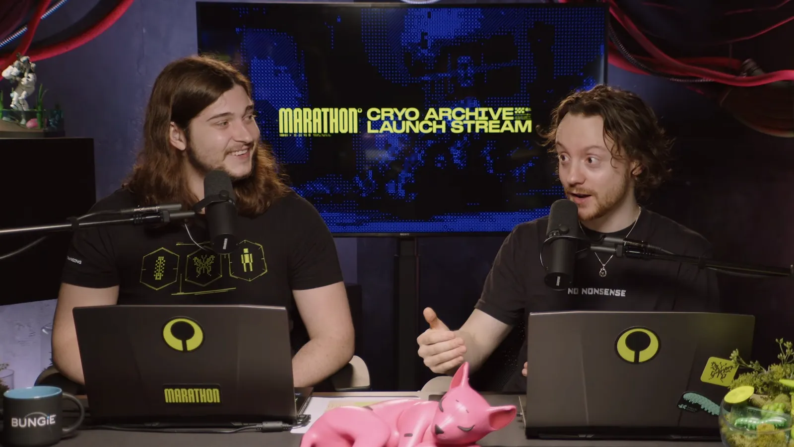 Milo and his co-host at the desk on the Marathon Cryo Archive launch stream, with the launch title on the screen behind them