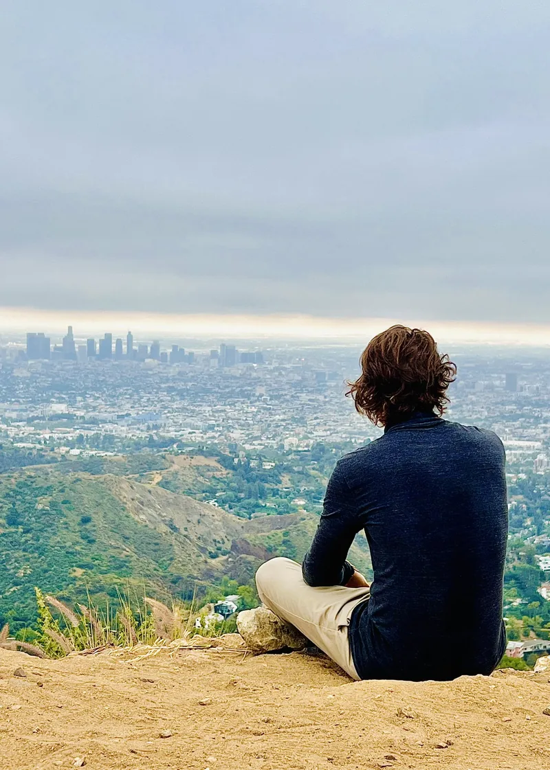 Person sitting on a hillside looking out over the Los Angeles skyline
